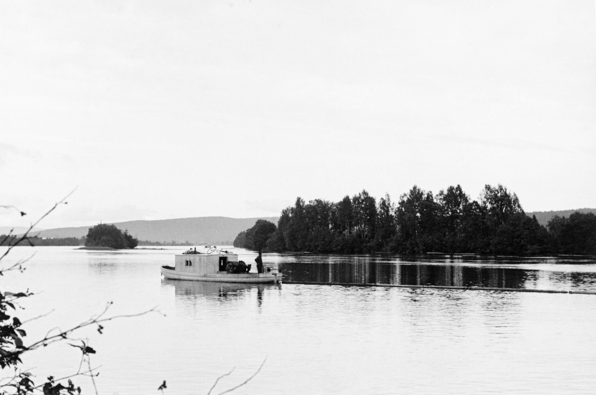 Varpebåten «Varp I», fotografert ved Gjersøyholmen, som ligger i Glomma i Sør-Odal kommune, sørvest for tettstedet Disenå.  Båten hadde et forholdsvis bredt og rundt skrog med et brakkeliknende overbygg over motor og mannskapsrom forut og en kraftig vinsj akterut.  Båten var malt i en lys farge.  «Varp I» eller «VB 51» ble bygd for Christiania Tømmerdirektion i 1914.  Fartøyet gikk i hovedsak i nedre Solør og på Storsjøen i Odalen.  Året etter at dette fotografiet ble tatt ble denne varpebåten transportert til Fetsund for ombygging og modernisering. 