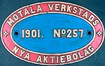 Oval loktillverkarskylt av mässing, målad i rött och blått med gula bokstäver. Text: "Motala verkstads Nya Aktiebolag. 1901. No. 257".

Modell/Fabrikat/typ: No 257, loknr. 18