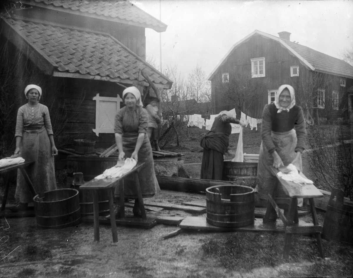Hildegard Pettersson med flera personer arbetar med tvätten i Sävasta, Altuna socken, Uppland