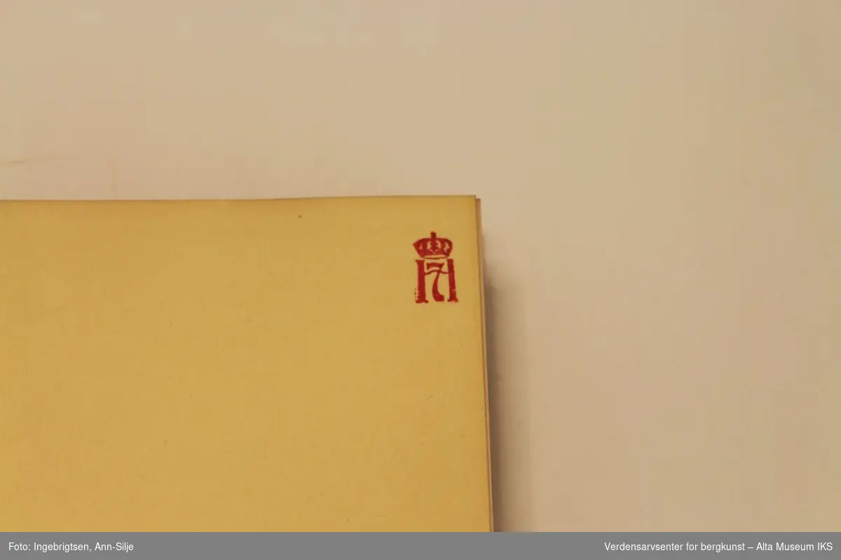 Innbundet bok med rød perm. På innsiden er det et rødt stempel med kong Haakon VIIs segl øverst på høyre hjørnet.