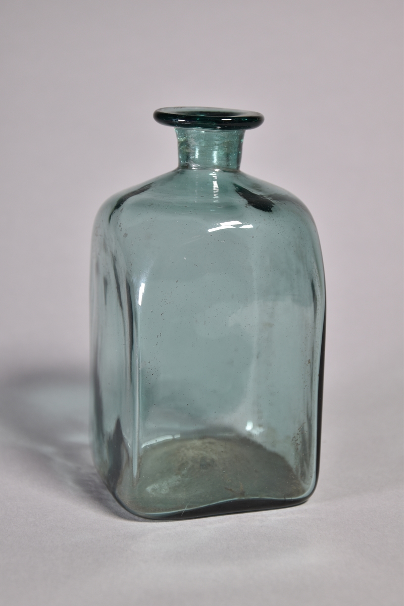 Flaska av grönt glas, kvadratisk, kort hals med utvikt mynning.