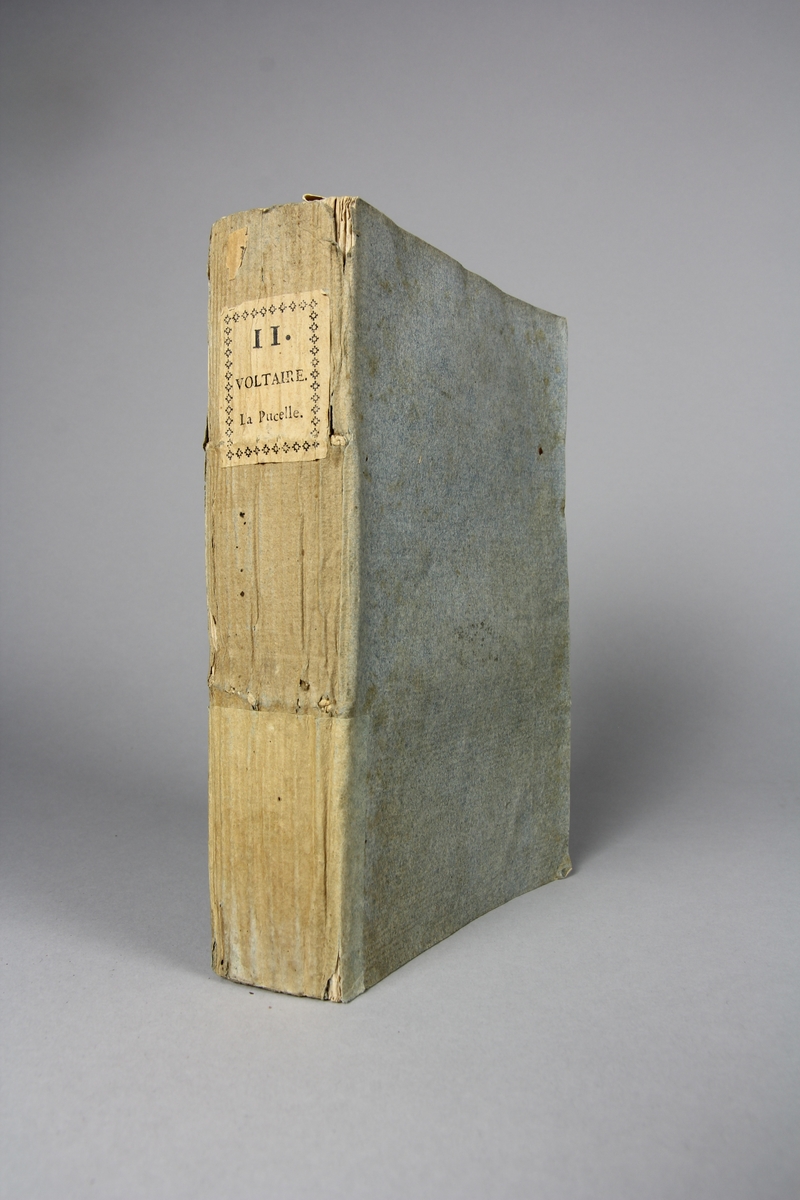 Bok, häftad,"Oeuvres complètes de Voltaire", del 11, tryckt 1785.
Pärm av gråblått papper, skurna snitt. På ryggen klistrad pappersetikett med tryckt text samt volymens nummer. Ryggen blekt.