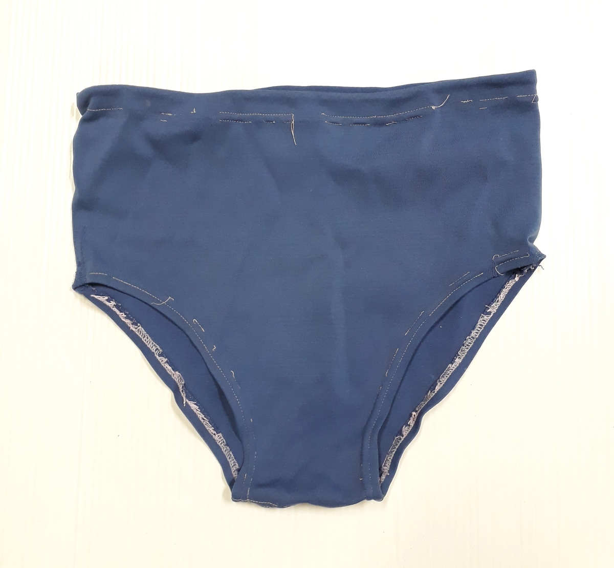 Blommig säck av galontyg innehållande badkläder: rutig bikini, blå badbyxor och blå/rosa bikinibyxor. Medföljde vid insamlingen av Vegan TERTIA.