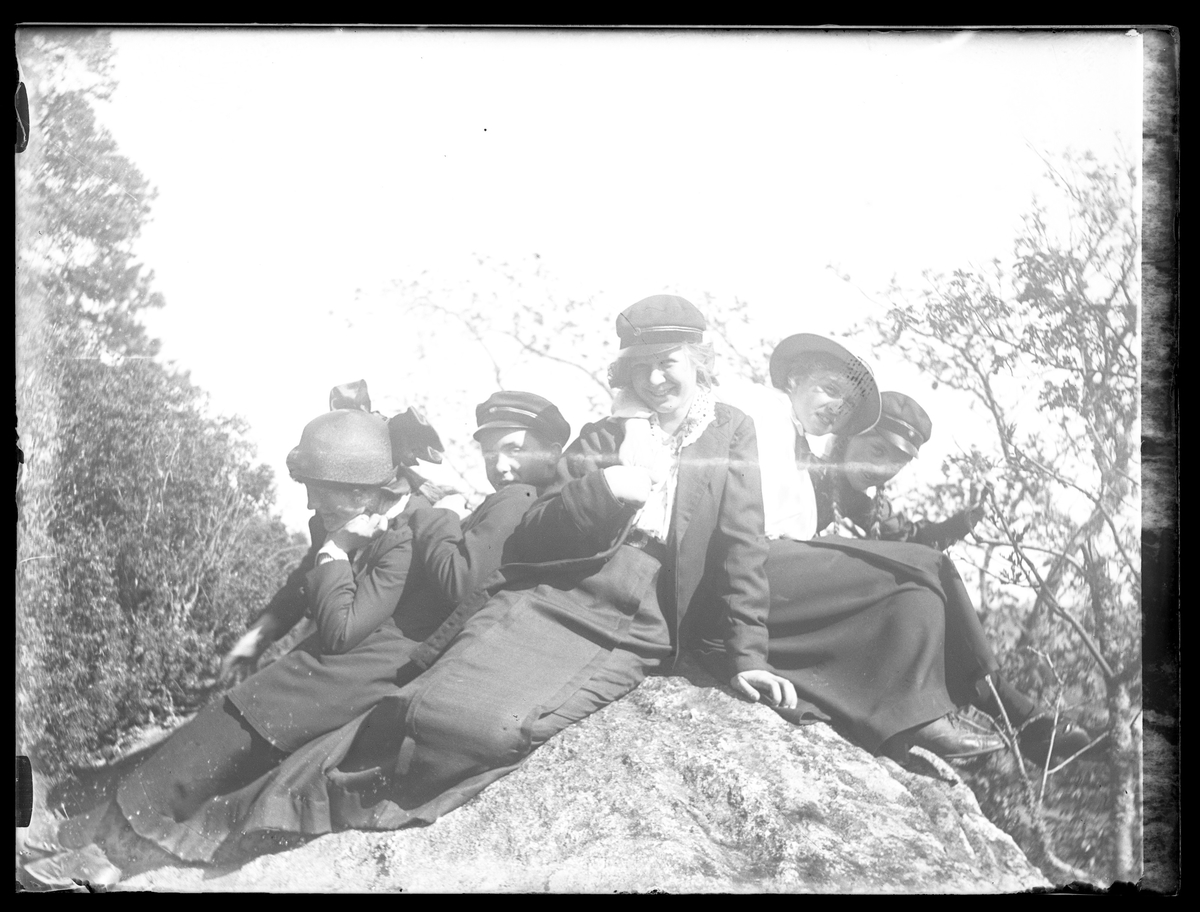 Fem flickor poserat på en sten i skogen. I fotografens egna katalog står antecknat "6:e klassens flickor".