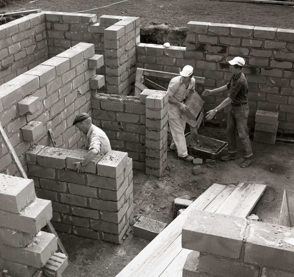 Tre män murar väggar av tegel vid byggnation av bostadshus vid gården Sunnanåker, 1967.