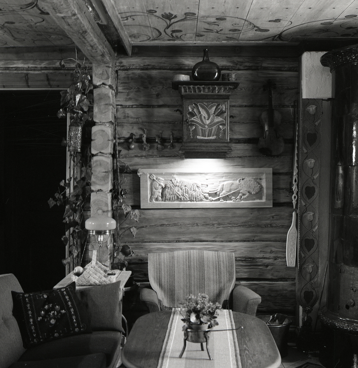 Interiör från gården Sunnanåker, våren 1972. Väggarna är av timmer. Där står en soffgrupp och på väggen hänger ett skåp och en trärelief.