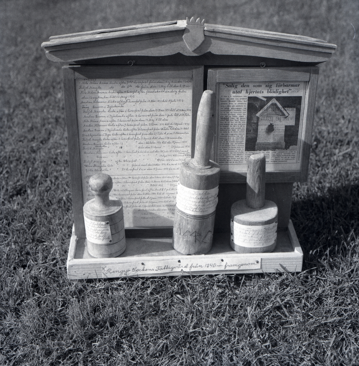 Modell av föremål på en bricka från John Westmäns samling. I bakgrunden syns en lång text.