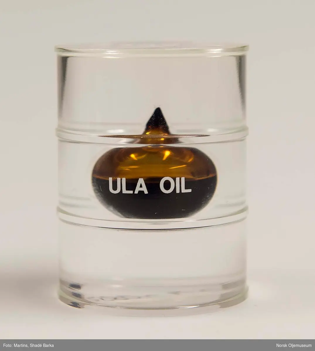 Oljeprøve i form av en dråpe støpt inn i pleksiglass formet som et oljefat.