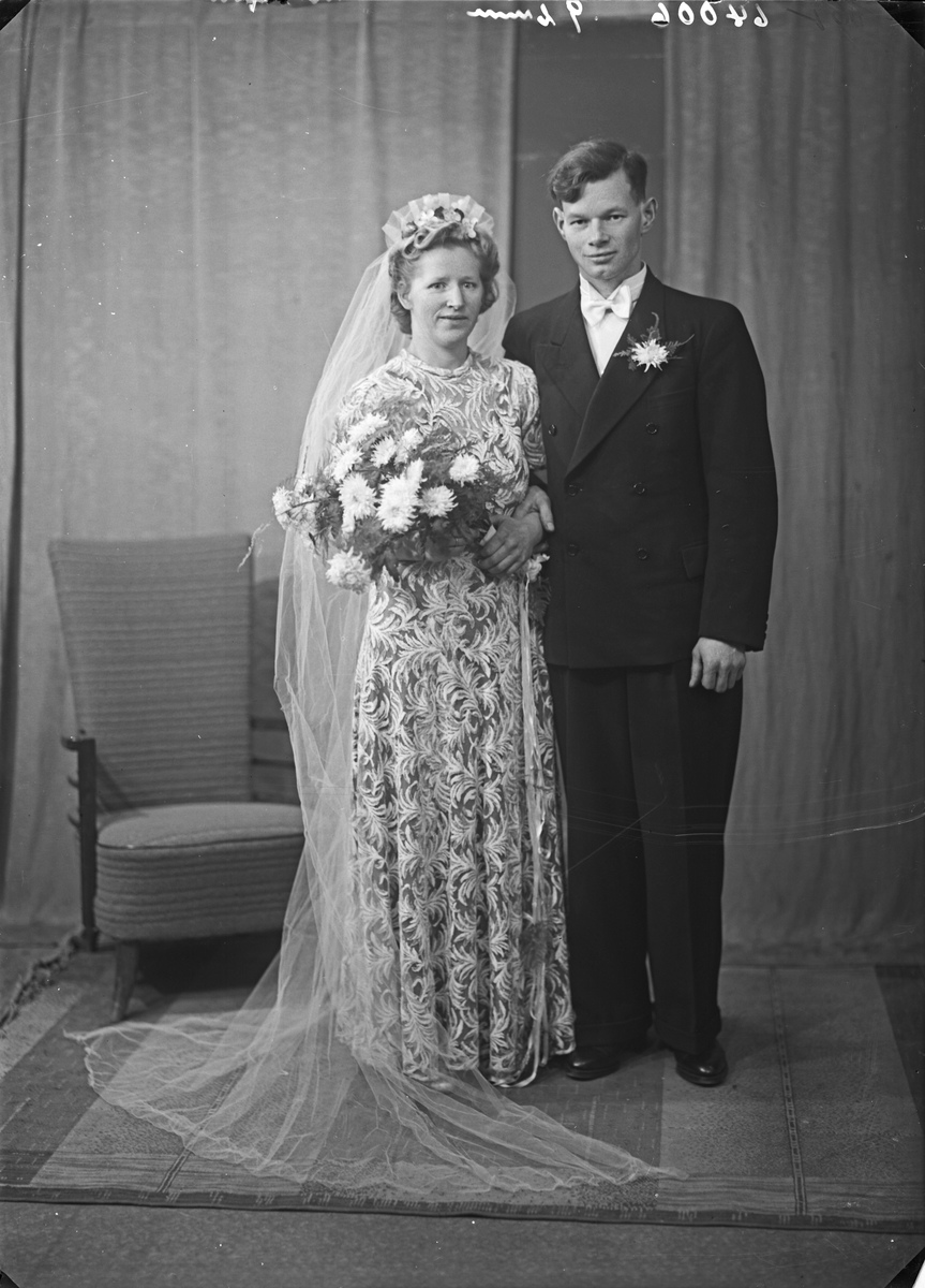 Portrett. Brudebilde. Ung kvinne i lys blomstermønstret kjole med slør og ung mann i mørk dress. Brudepar. Bestilt av Hr. Berht Berthsen. Haugeveien 52