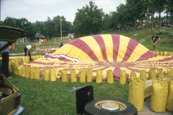 75-årsminnet av Andrées Nordpolsfärd firas med Ballongdagen på Åsavallen i Gränna 1972. En ballong ligger utlagd på gräsplan med gula ballastsäckar runtom, den håller på att fyllas. Ballongen är möjligen gasballongen Gatzweiler Alt. Diabild.