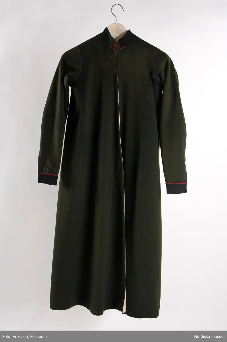 Långtröja för kvinna, helskuren, av grönsvart kläde med svarta ärm-och halslinningar med passepoaler av röd vadmal, helfodrad med vit hemvävd bomullslärft.

Berit Eldvik juni 2005