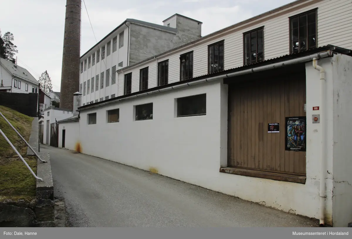 Del av produksjonslokala til Salhus Tricotagefabrik (1859-1989) bygd i 1863/1938. Brukt som produksjonslokale då fabrikken var i drift. Første etasje var ullblandingsrom med plys, andre etasje var brukt som lager.