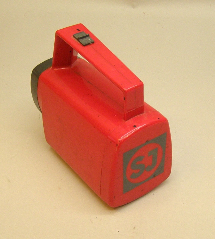 "Standardficklampa" av röd plast med SJ-märkning i bakre änden.

Historik: Ficklampor av denna typ användes av SJ:s personal på expeditioner och lokförarhytter m.m, från ca 1980-talet  och fram till åtminstone 2008.