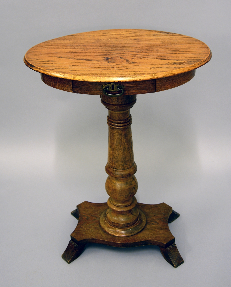 Lite, ovalt sybord med skuff, står på én søyle plassert på en plate med fire nokså små ben.
