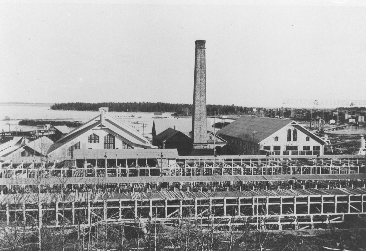 Norrsundets sågverk. Plank- och brädmattorna vid sågen revs i början av 1960-talet. Kranen på Granskär i bakgrunden.