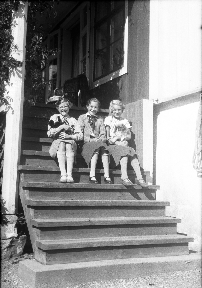 Tre jenter sitter på trapp