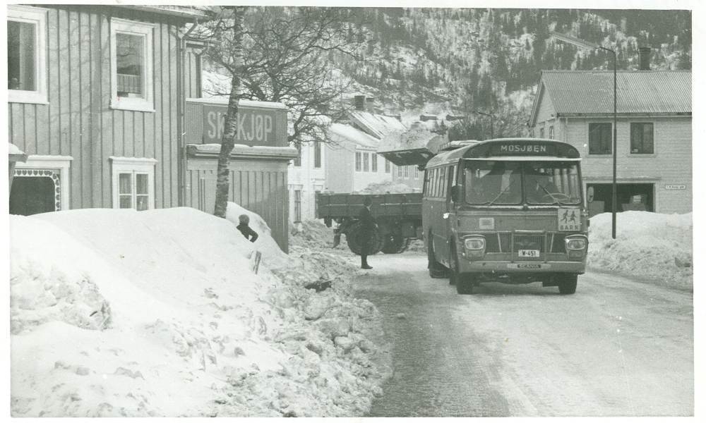 Vinterbilde fra Skjervgata, 1976. Det var vinter før også. Bussen (W-451) er parkert midt i gata. Scandia 1968-modell tilhørende Helgeland Bilruter A/S.