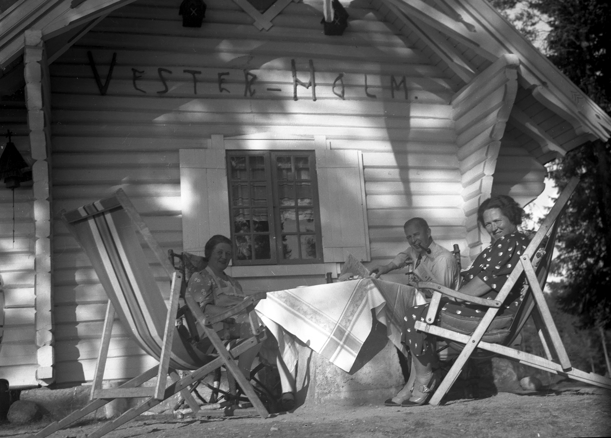 Mennesker sitter ved tømmerhus,Vester-Holm