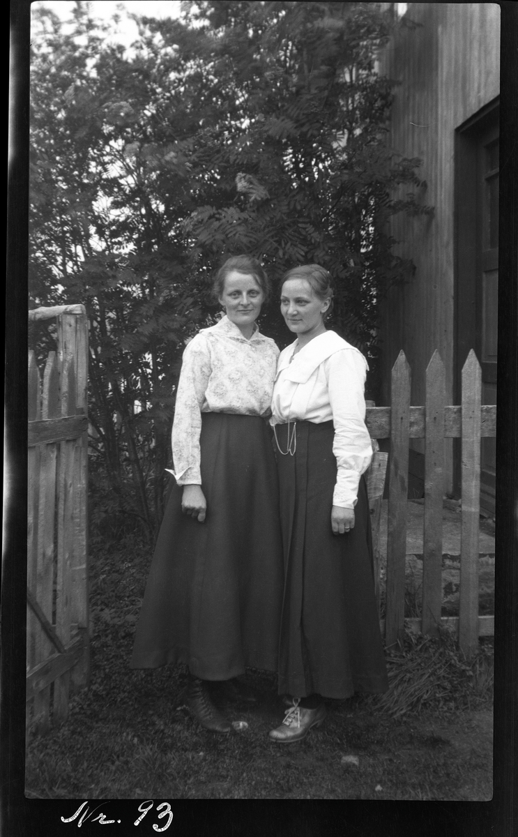 Portrett av to kvinner ved hageport.