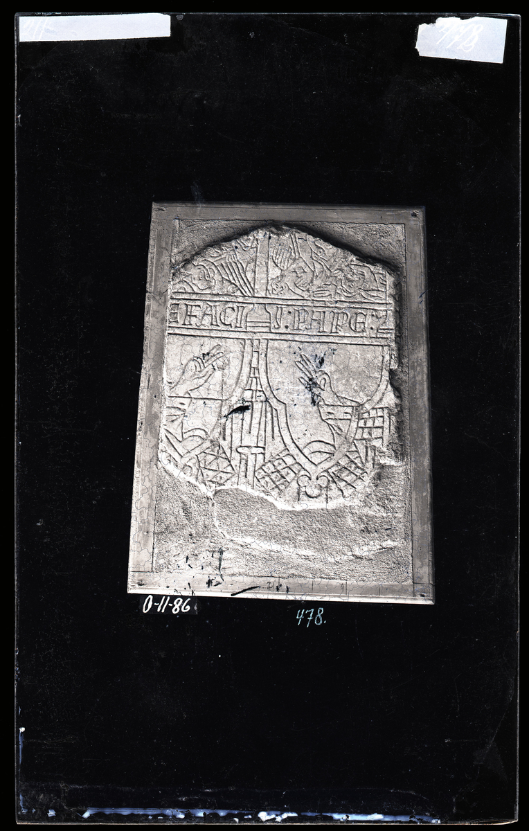 Middelaldersk (tidlig 1300-tall) gravstein fra Nidarosdomen. Trekløverbuer under tak og tårn. Inne i buene Guds hånd som velsigner. Figurer i feltene under teksten. 

Tekst: ... EFACII : PAPE

"Pave Bonifacius"