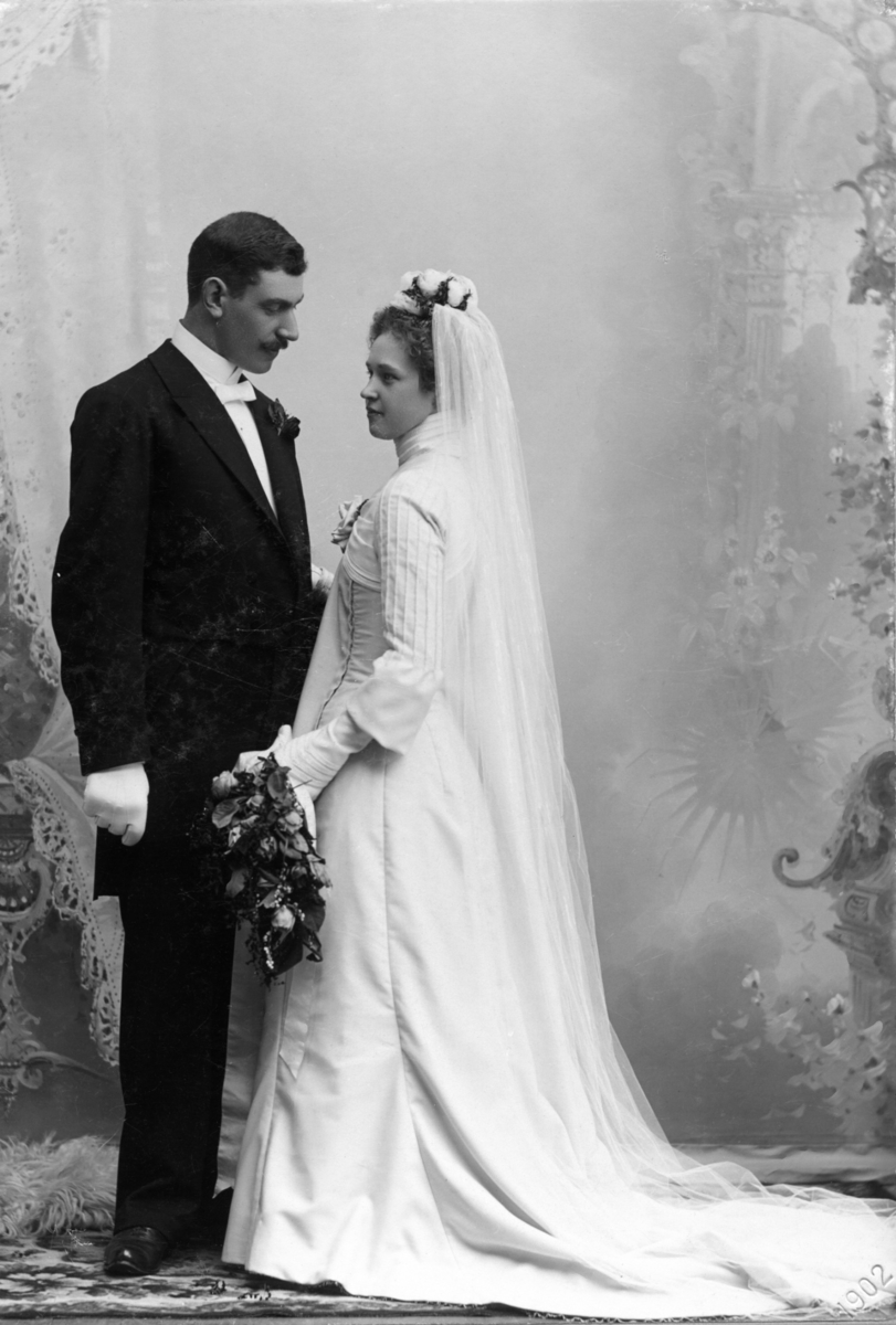 Bröllopsfoto av brudparet Ellen och handlanden Oscar Pehrson. Brudgum klädd i frack, bruden har lång klänning, slöja, krona och brudbukett.