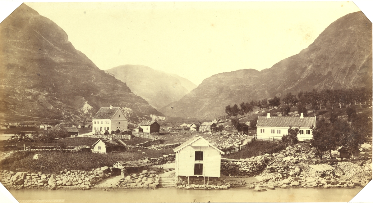 Skjolden, Luster i Sogn. Kystbebyggelse med bolighus, uthus og naust. Fjellandskap i bakgrunnen. Fotografert  mellom 1870 og 1886.