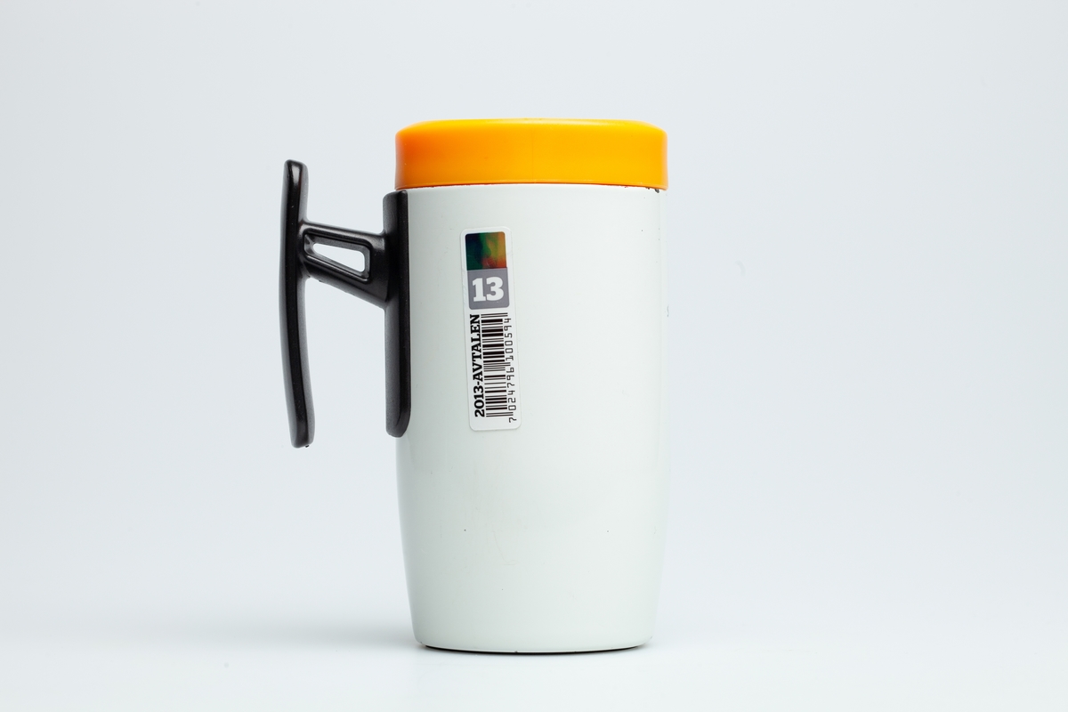 En hvit Statoilkopp med sort hank. Statoillogo i oransje på koppen. På en etikett på koppen er en Statoillogo, en strekkode og tallet 13.