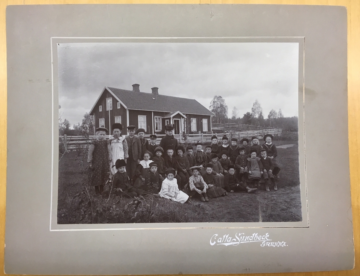 Folkskolelärarinnan Charlotta Kristina Johansson med skolbarn, sittande och stående framför Mörstorps skola.