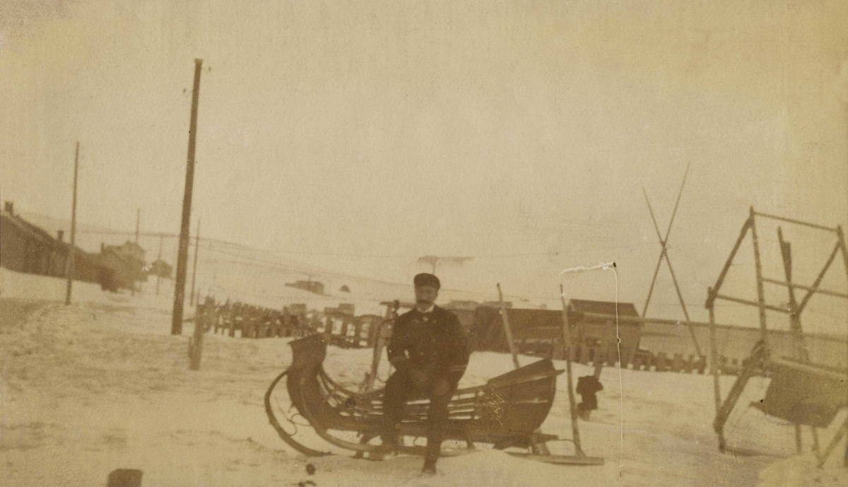 Sjømann på tur i Vadsø  sittende på en slede. Antatt Hvistendahlsgt. 1917-1918.