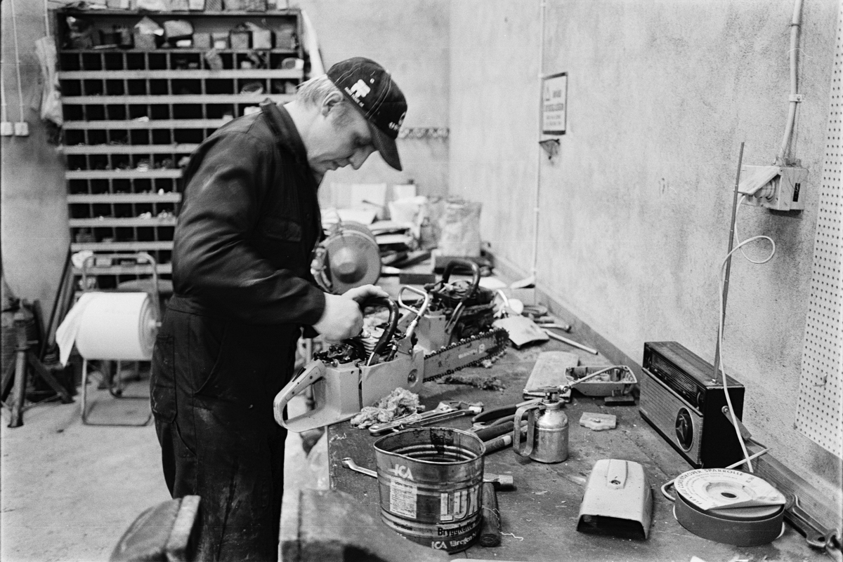 Traktorförare Folke Sundnäs reparerar en motorsåg i verkstaden, Hacksta gård, Enköpings-Näs socken, Uppland november 1981