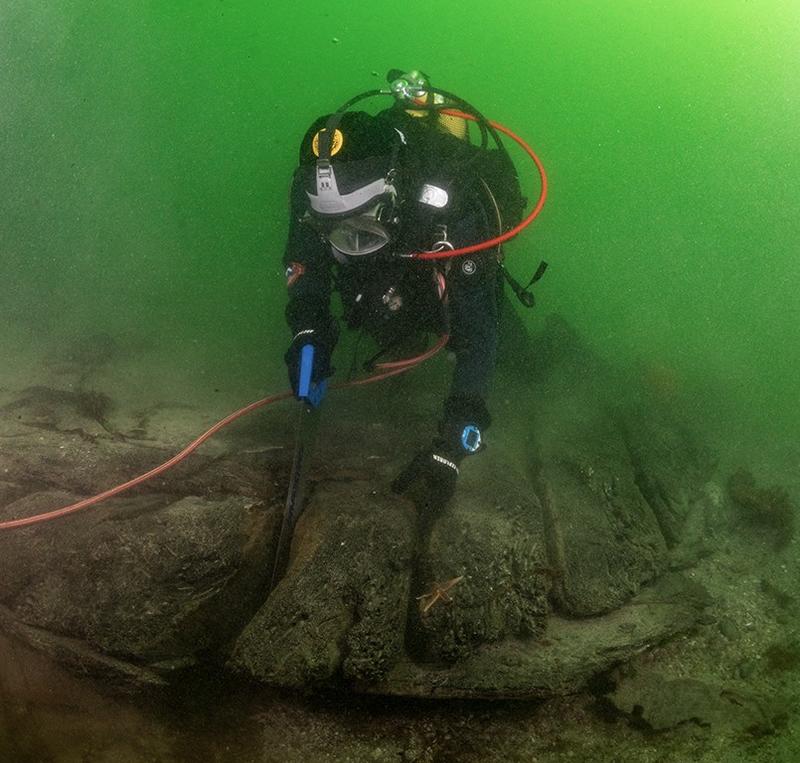 Dykker under vann sager i vrak på sjøbunnen: Arkeolog Elling Utvik Wammer sager ut skiver av hudbord til datering av skipsvraket ved Drengeholmen. (Foto/Photo)