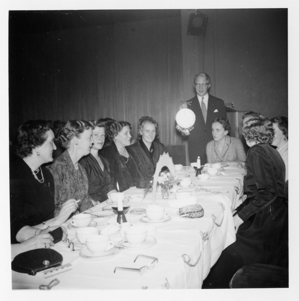 Deltagare sitter vid ett dukat kaffebord under ett möte med Fredrika-Bremer Förbundet 1957.
