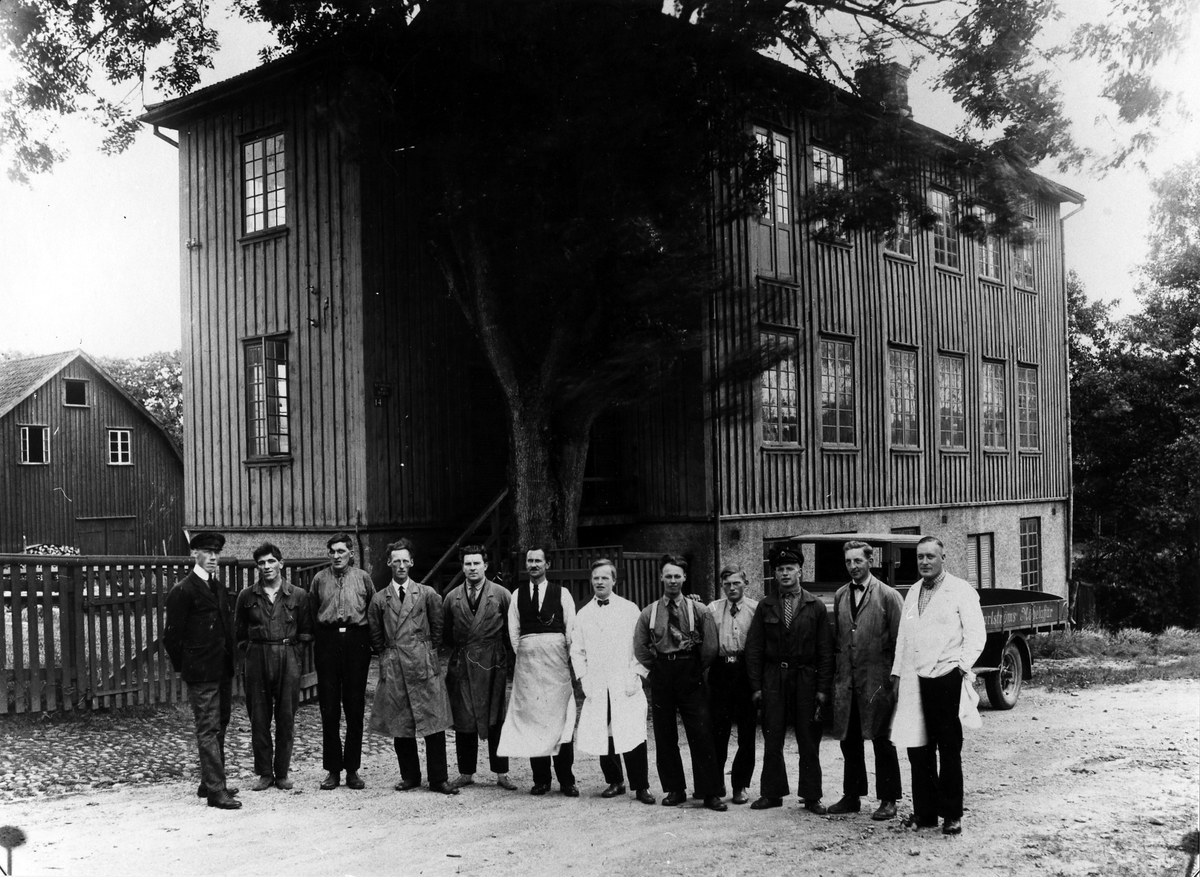 Gruppbild på personalen på Ruben Carlströms Möbelaffär framför ett trähus på 3 våningar.