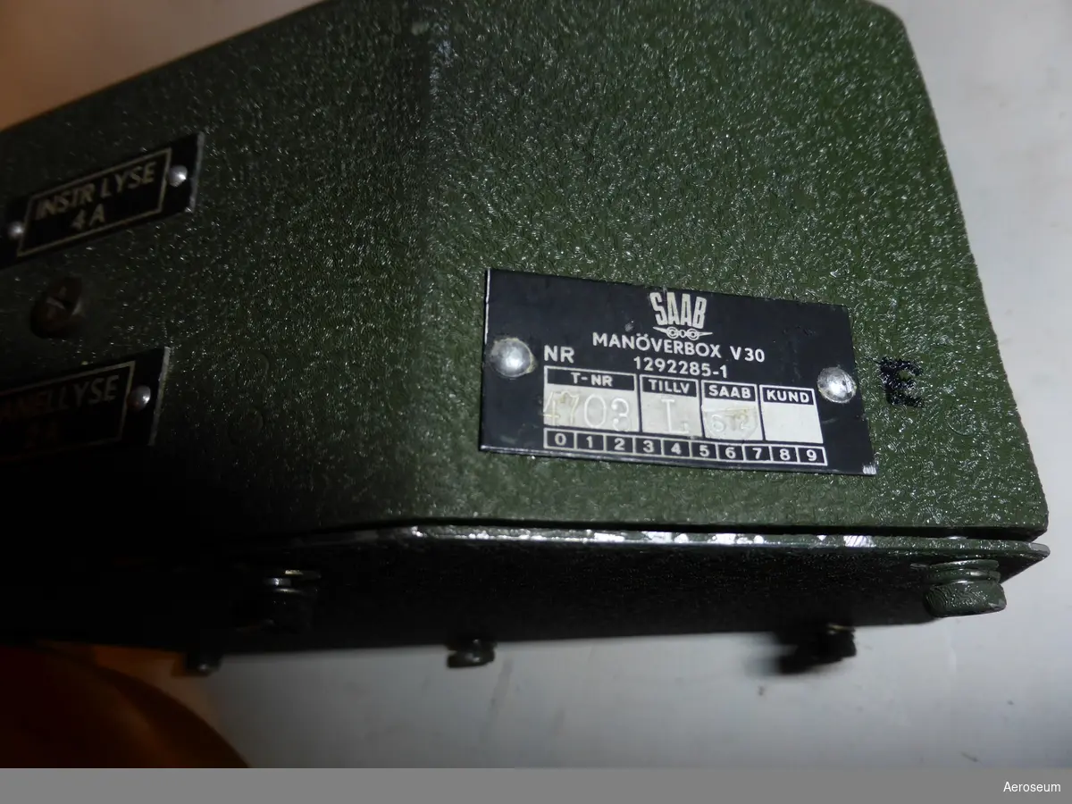 Manöverbox för J 35 (Draken). Gjord i grön krymplack.

På föremålet står det på en liten skylt på en av sidorna: "SAAB MANÖVERBOX V30 NR 1292285-1", "TNR 4703", "TILLV L", "SAAB 573".