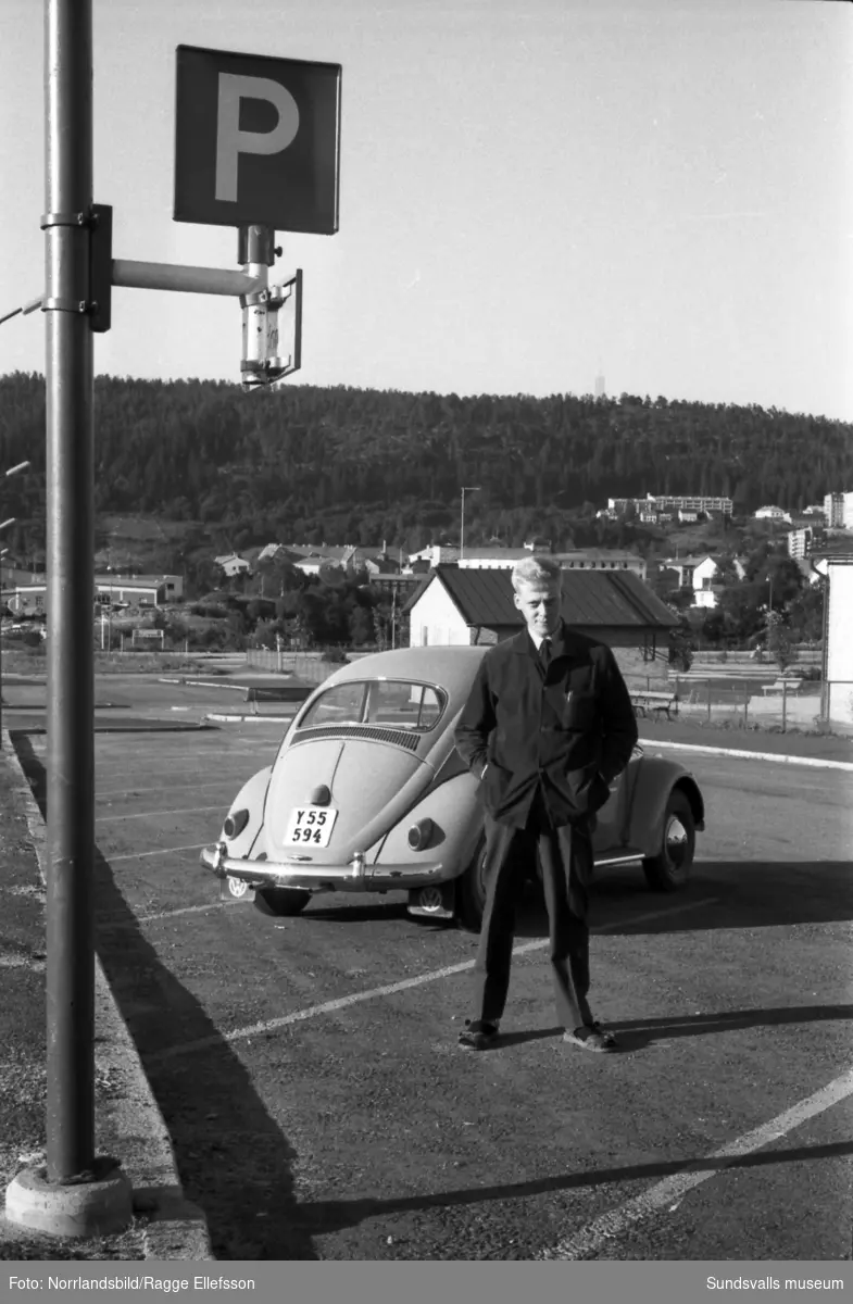 En man (Bexell) står invid en Volkswagen Bubbla på parkeringen utmed Lekängsvägen i Sallyhill.