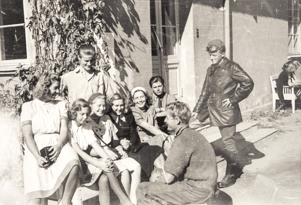 Norske polititropper står sammen med en gruppe kvinnelige sivile utenfor et hus, våren 1945.