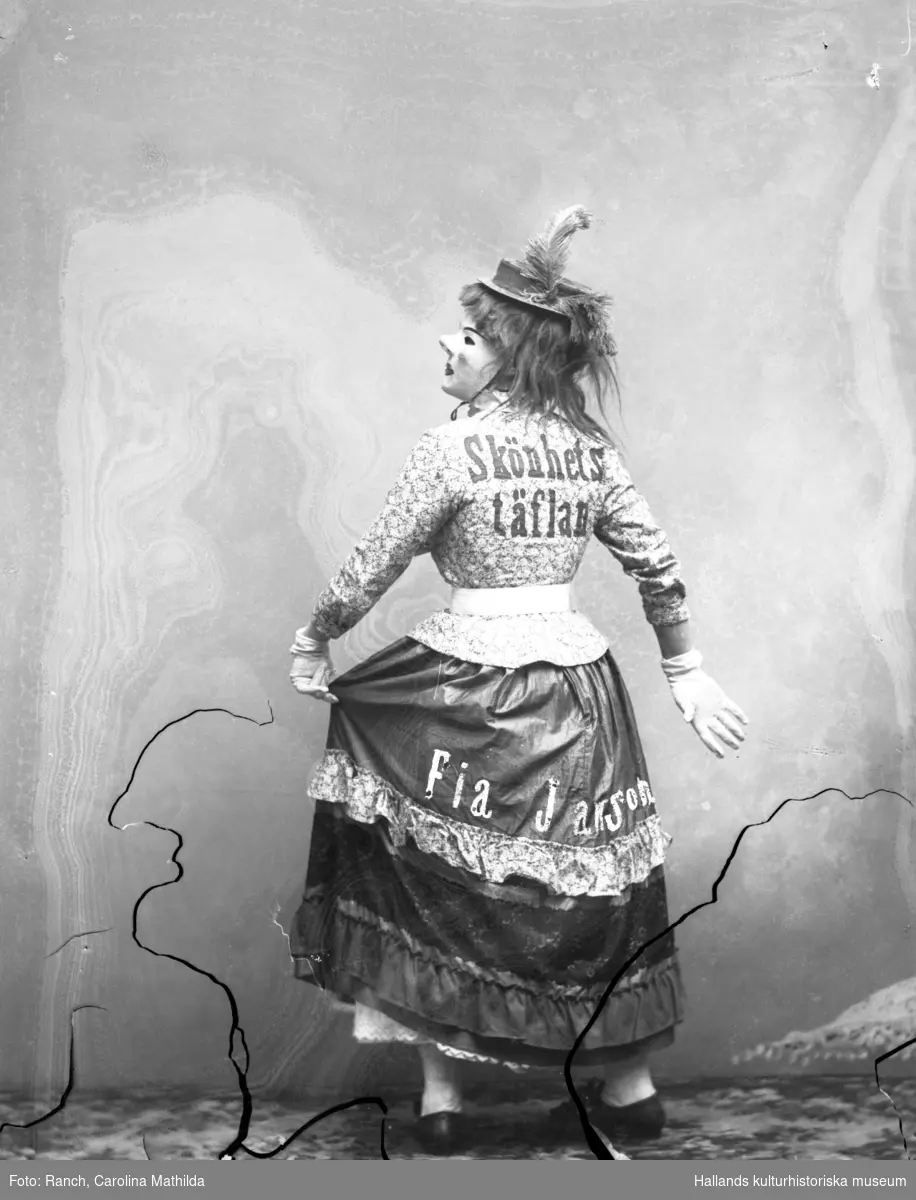 Mathilda gestaltar revyfiguren Fia Jansson, känd bl a från Emil Norlanders revy "Den förgyllda lergöken". På ryggen står: "Skönhetstäflan" och på kjolen "Fia Jansson".