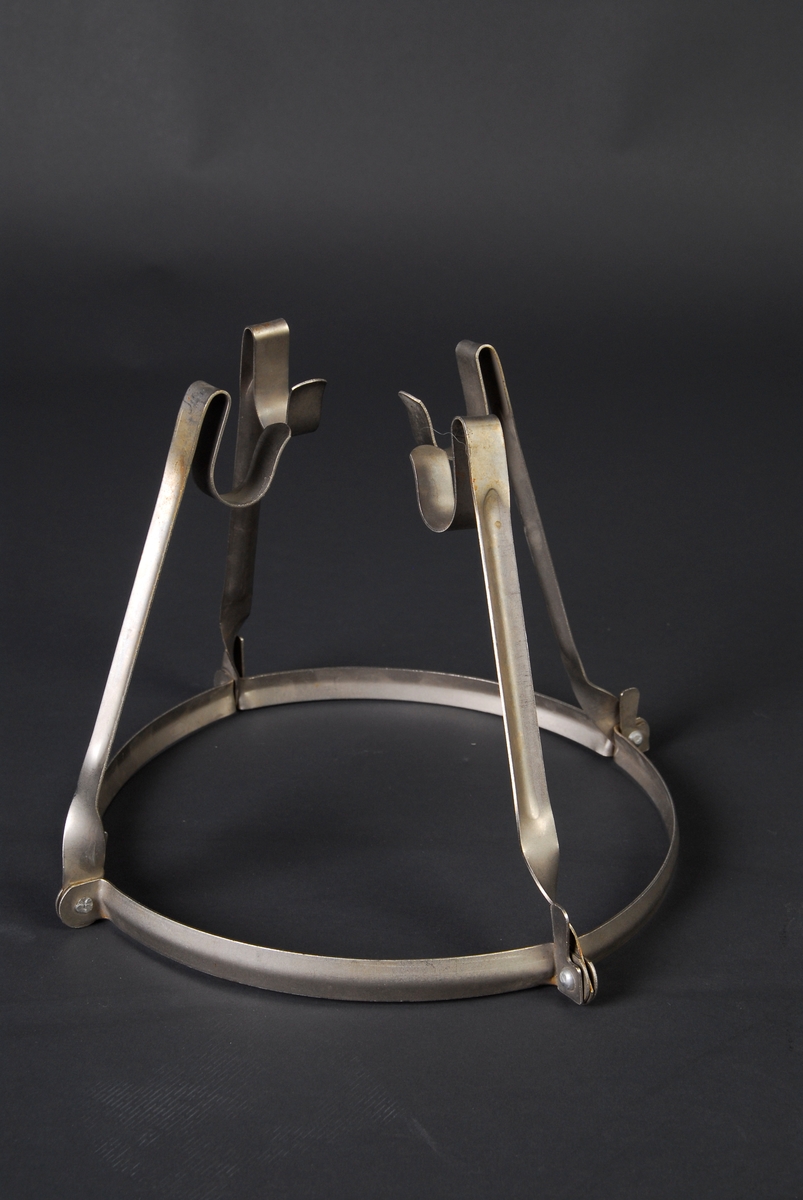 Ring, med 4 hengslete bein til å slå ut, stativet kan plasseres på kanten av en kjele og et safteklede spennes over. 