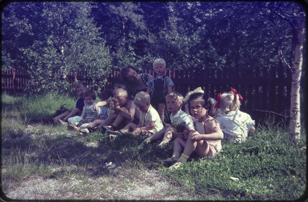Kippermoen barnepark, 1961-62. Mange barn som sitter med blomster i gresset.