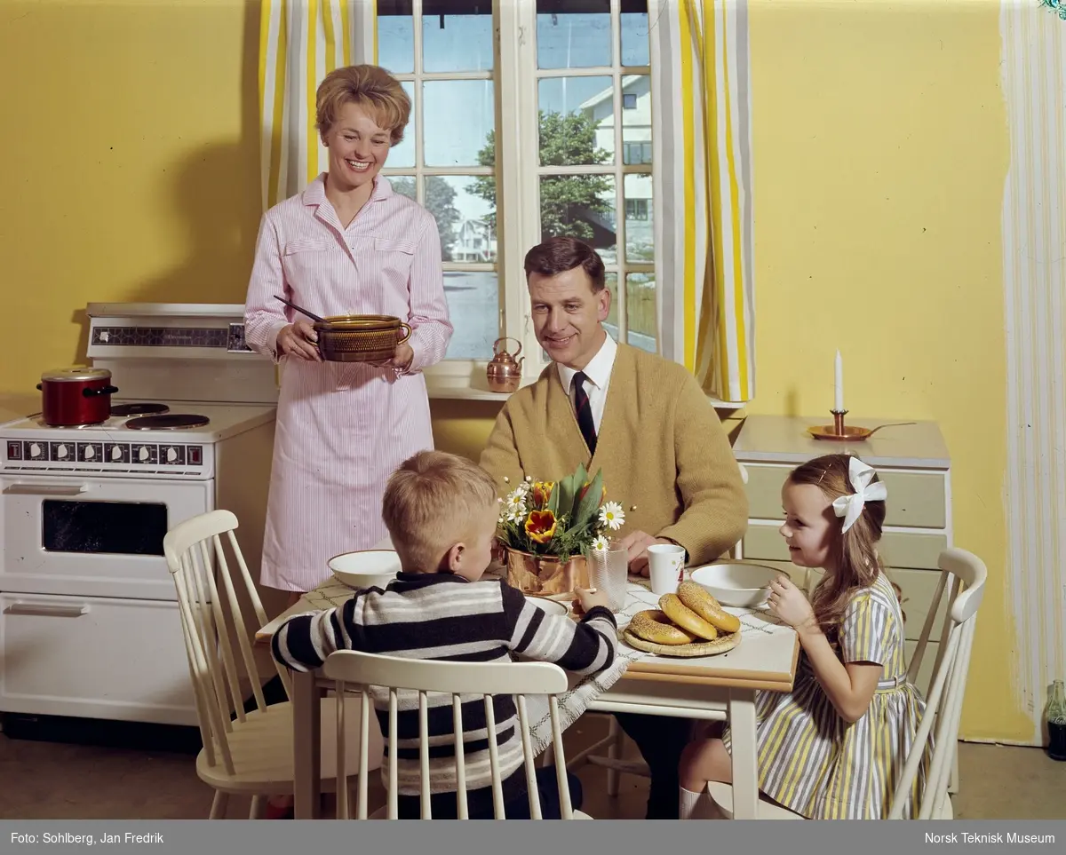 Illustrasjonsfoto, en "familie" klar for middag i kjøkkenet. En mann og to barn, ei jente og en gutt, sitter ved spisebordet, mens kvinnen står bak klar til og servere fra ei gryte.