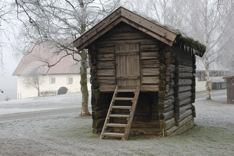 Bildet viser kjona ute om vinteren. Det er rim på bakken og det er kaldt. Kjona er et høyt hus som er laftet.