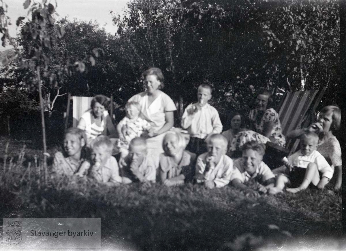 Barneflokk og tre kvinner med fluktstoler i hage