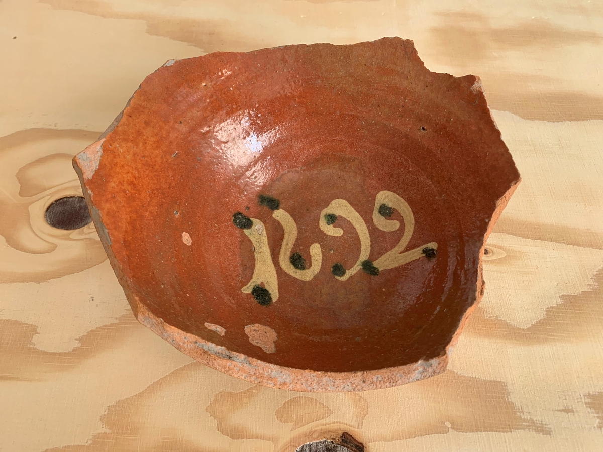 Botten till skål, brunlaserad. I botten är årtalet 1692.