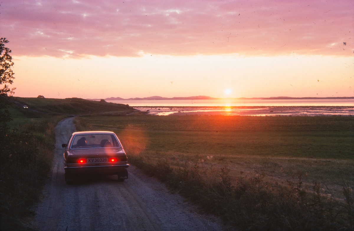Bil i solnedgang ved kysten.