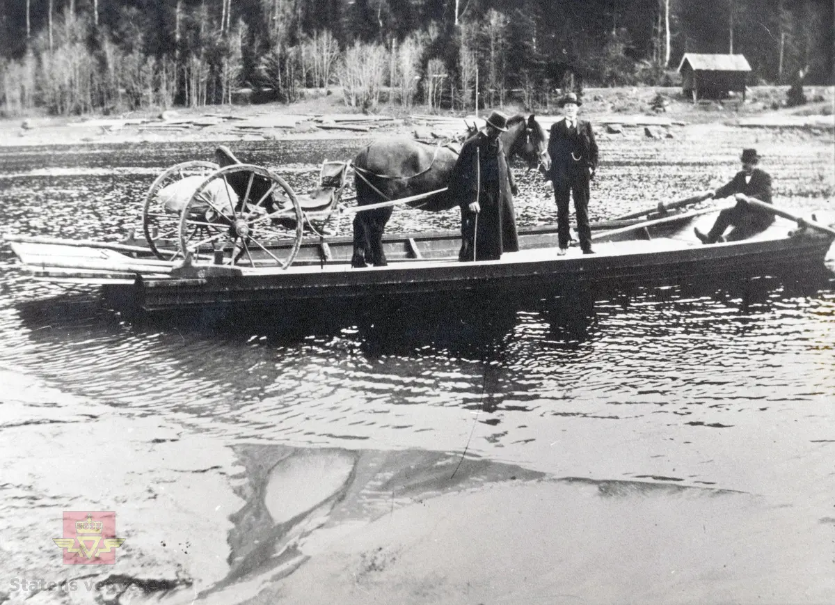 Ferje ved Bergsundet nær Hallingby i Ådalen rundt 1900. Ferjemannen ror, transporterer hest med trille, skysskar og passasjer. Passasjeren i frakk kan ha vært lensmann Johan Aslaksrud.