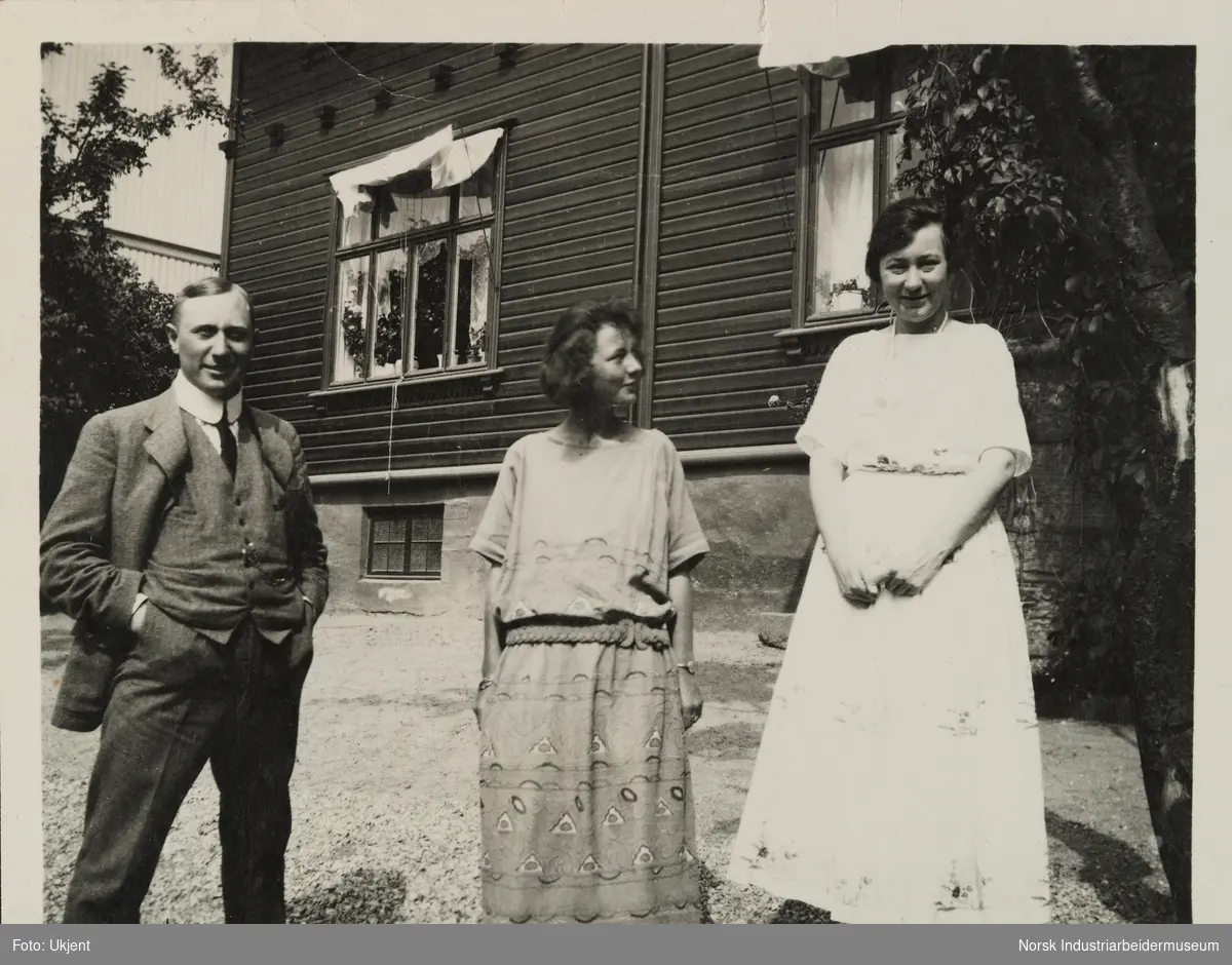 En mann og to kvinner står på gårdsplass foran bolighus i Skottland