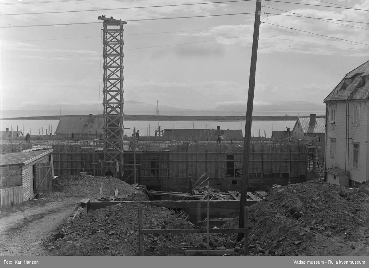Vadsø nye sykehus i Oscarsgate 29, forskaling under byggeprosessen i 1959. Litt av Vadsø gamle sykehus vises til høyre. Vadsøya med luftskipsmasta ses i bakgrunnen.