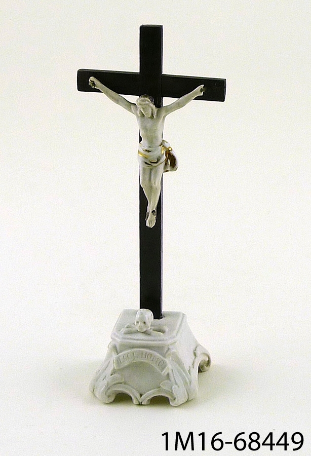 Krucifix, den korsfäste och foten på föremålet är av porslin. Inskription på föremålets fot: "ECCE HOMO".
