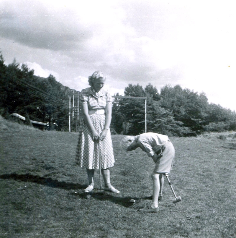 Mabel Larsson (född 1935) och Benny Andreasson spelar krocket på en gräsmatta, 1950-tal. De var sommargäster från Majorna i Göteborg som hyrde Hallen 1:4 "Josefs" "Kobacken".