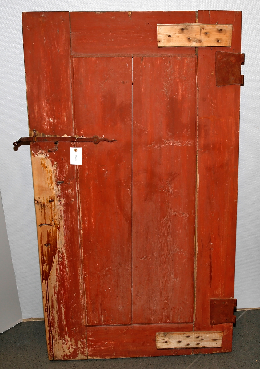 Rød omramming med ett avlangt dørspeil. Dørspeilet er lyseblått med blå trær.  Dørklinke med håndtak med fint utarbeidet jern. To dørhengsler.
